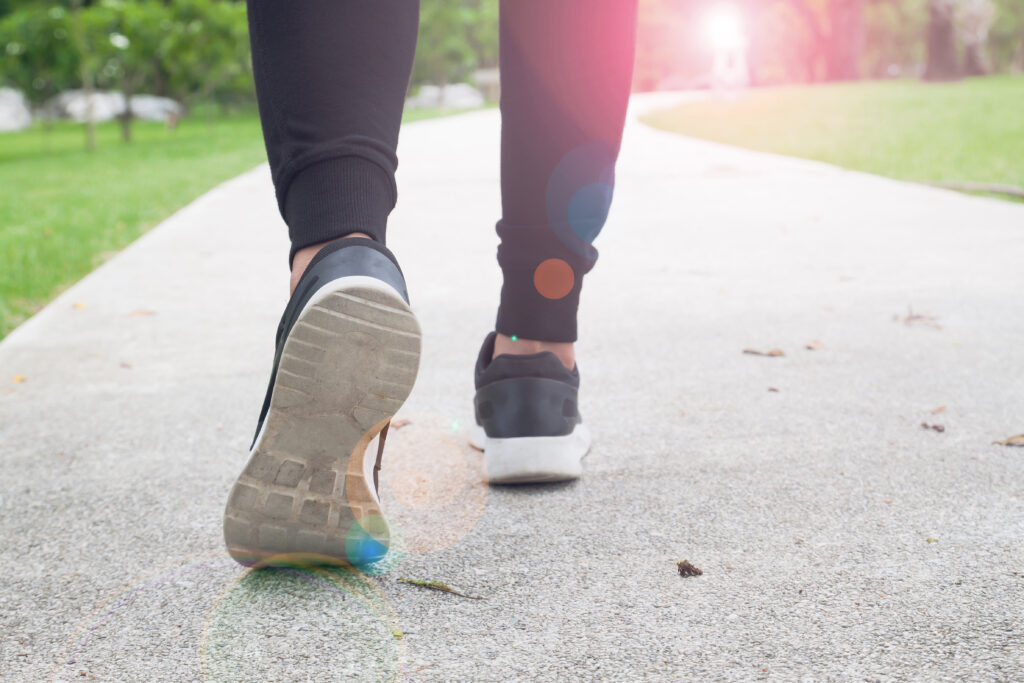 Close-up of a person walking on a paved path in a park.