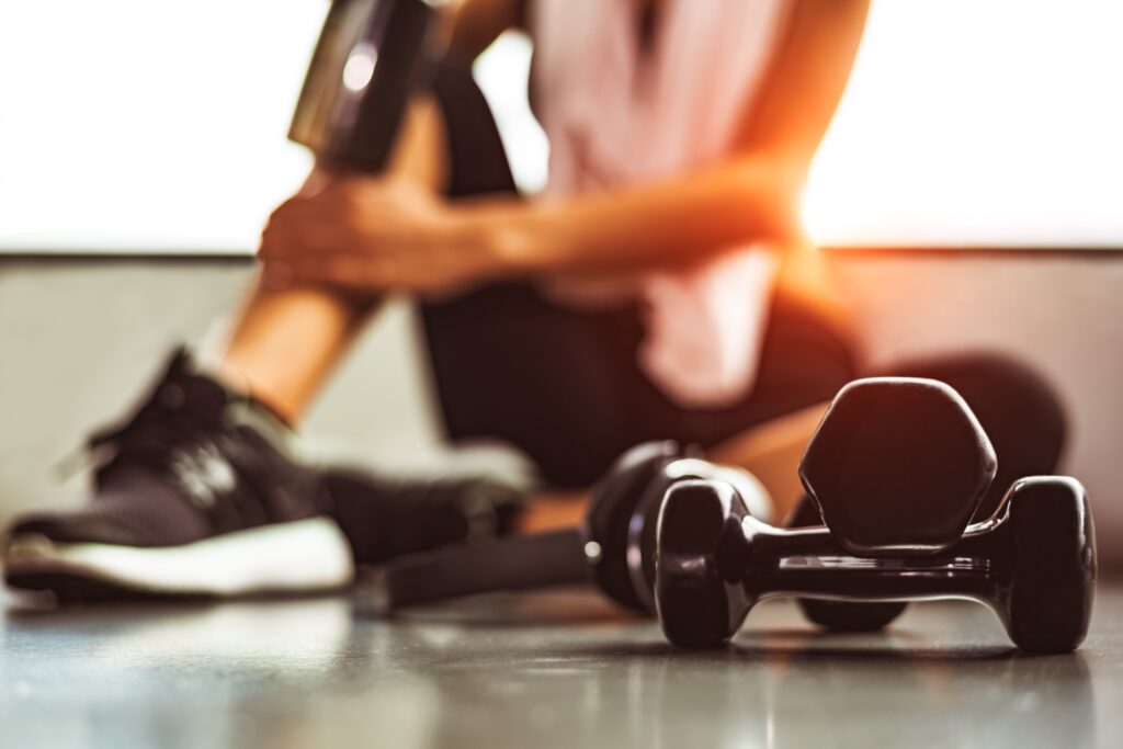 woman sitting next to dumb bells indicating weight loss workout